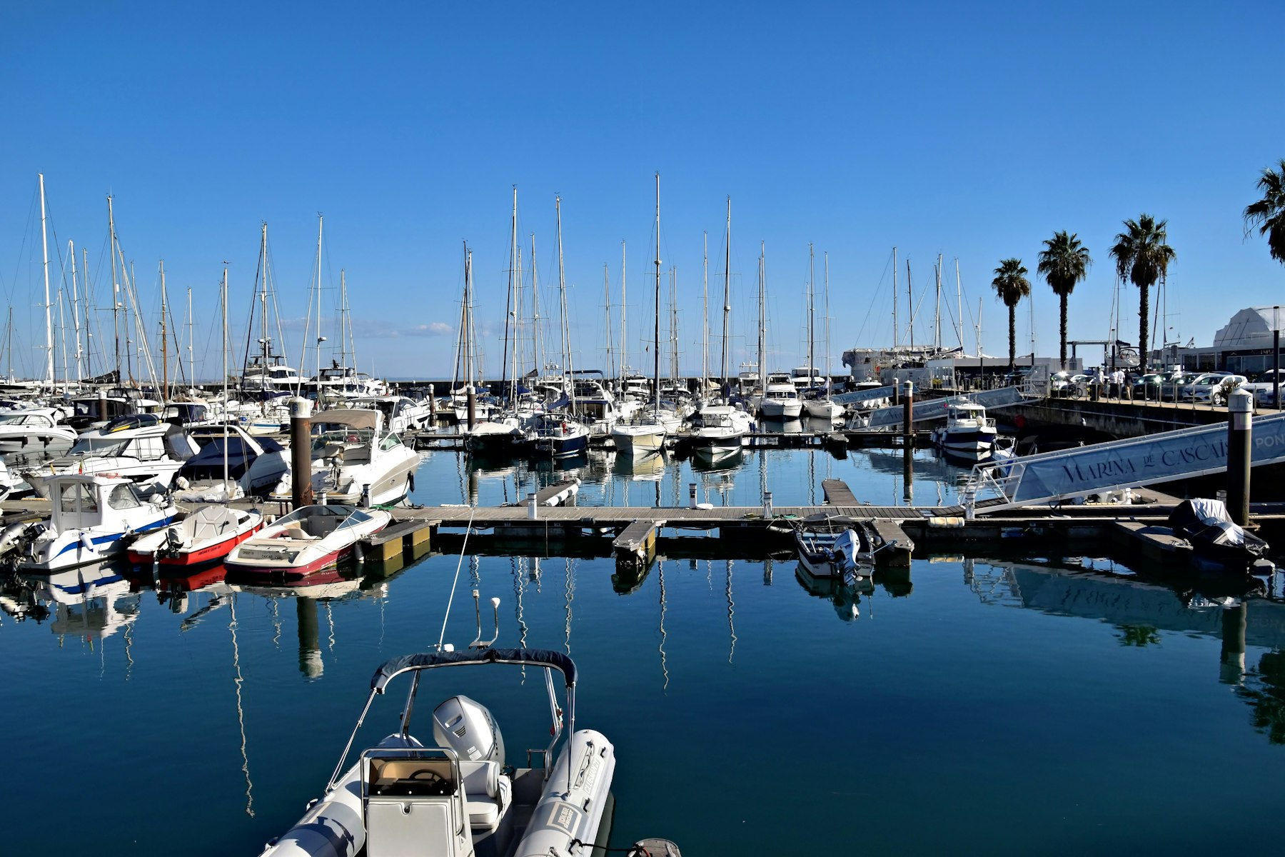 Sailboats and yachts docked in a marina under a blue sky