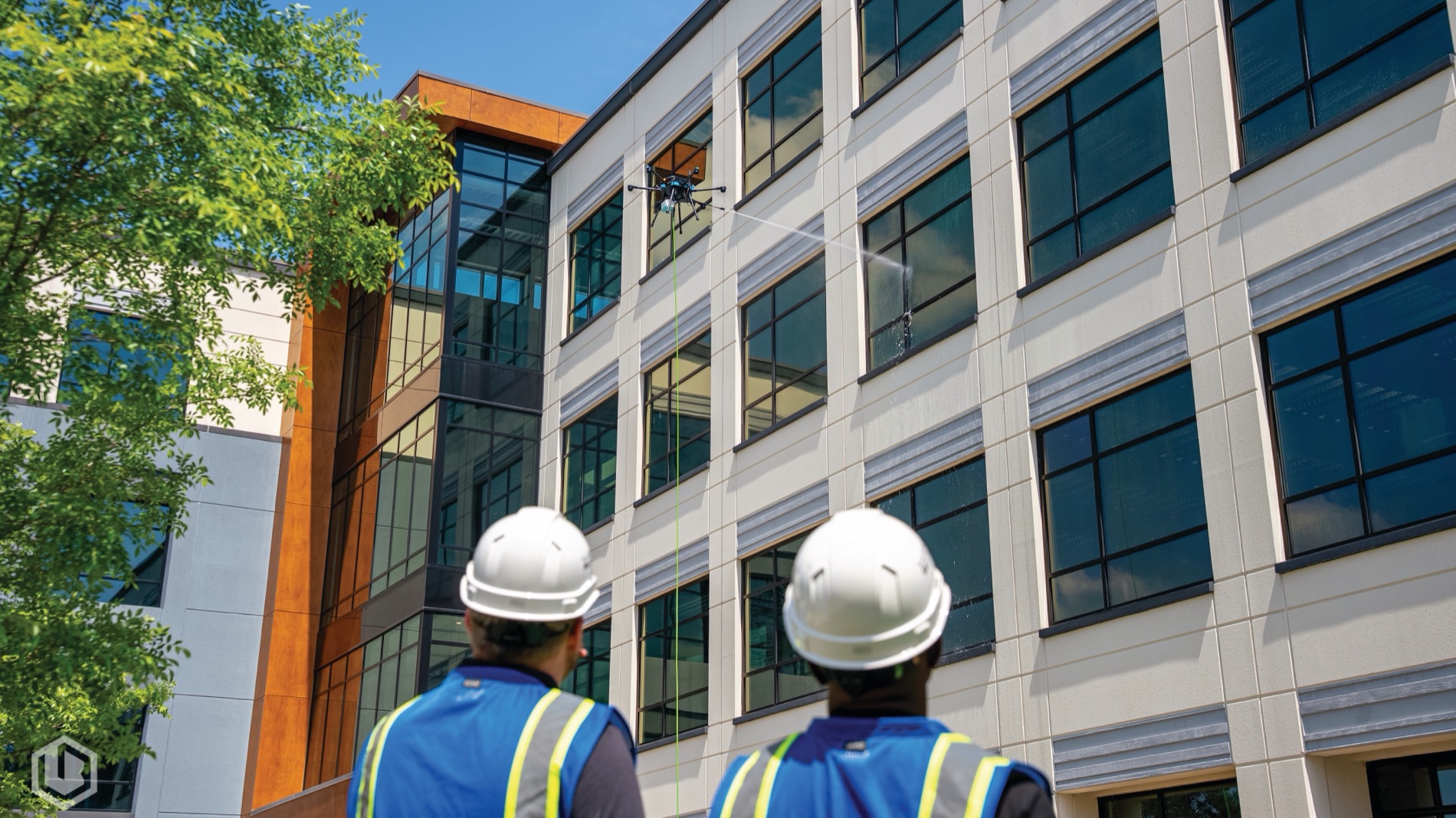 Two SPRKL crew in hard hats and hi-vis assessing a building elevation from the ground