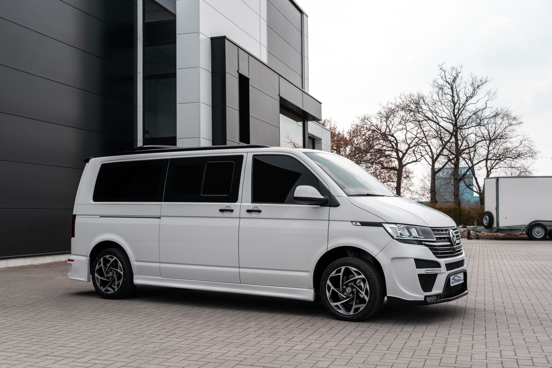 A single clean white commercial van parked beside a modern building in daylight